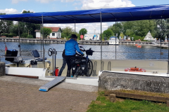 Erich hebt sein Fahrrad auf die kleine Fähre am Kanal