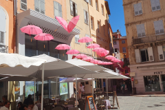Côte d’Azur Reise Grasse entdecken. Ein schöner Tag beginnt. Rote Regenschirme in der Altstadt