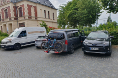 Abfahrbereite Fahrräder am Autoheck vor dem Hotel