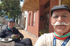 Erich und Werner sitzen in der Sonne vor der Bäckerei mit Kaffee und Kuchen