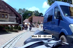 Blauer Transporter überholt Radfahrer mit extrem geringem Abstand in enger Ortsdurchfahrt – lebensgefährliche Verkehrssituation