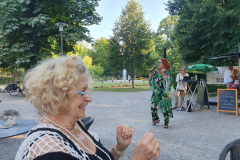 Lou Hoffner singt im Freien vor einer sommerlichen Gartenkulisse