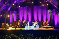 Konzertszene: Vicky Leandros inmitten ihres Orchesters vor beeindruckender KulisseKonzertszene: Vicky Leandros inmitten ihres Orchesters vor beeindruckender Kulisse