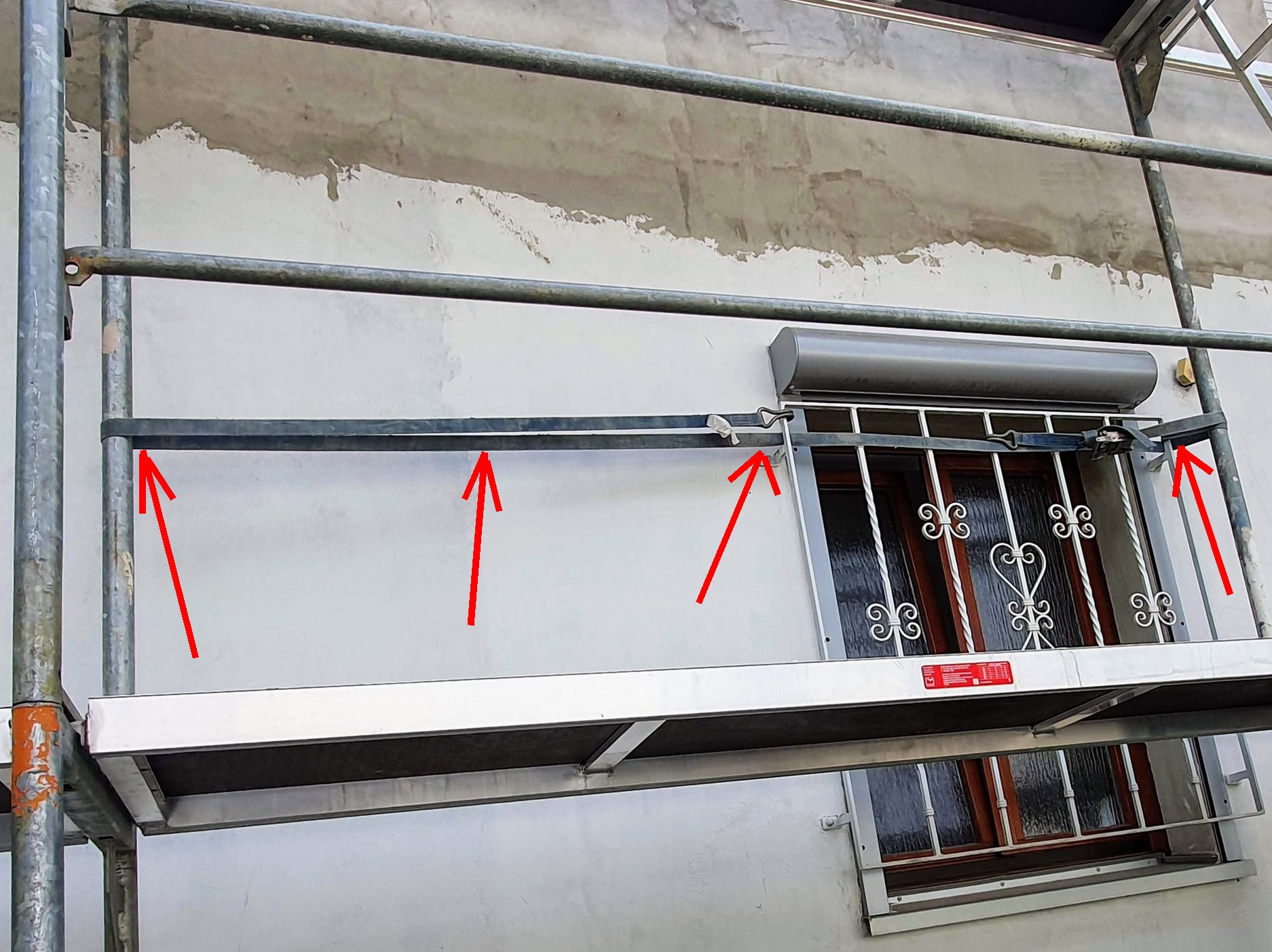 Gerüst mit Montagegurt an Fenstergitter festgezurrt