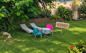 Reservierter Schattenplatz mit zwei Liegen und Tisch in der Gartenanlage einer Apartmentanlage in Maspalomas Dunasol